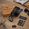 A black leather belt, its box, and accessories are laid out on a wooden surface. Produktbild-Vorschau