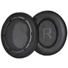 Two black ear pads for headphones are shown against a white background. One ear pad is slightly angled, revealing the mesh interior and the letter 'R' embossed on it. The other ear pad is shown from the side, with its mounting mechanism visible. Produktbild-Vorschau
