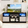 A modern black TV stand with LED lighting, featuring a television, a record player, decorative items, and storage compartments. Podgląd zdjęcia produktu