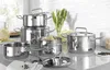 A set of polished stainless steel pots and pans are arranged on a countertop with some vegetables and peppercorns. Produktbild-Vorschau