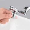 A hand is holding a faucet extender over a sink, with water spraying from it. Náhled obrázku produktu