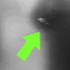 A bright green arrow points to a small, indistinct white shape against a dark background, with a lighter gray area on the left. Produktbild-Vorschau