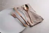 A set of copper-colored cutlery is arranged on a plate and a napkin. Podgląd zdjęcia produktu