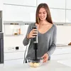 A woman is using an immersion blender in a kitchen. Podgląd zdjęcia produktu