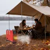 A couple is having a meal under a tent by a lake, with a red diesel heater in the foreground emitting smoke. Náhled obrázku produktu