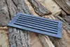 A cast iron grate rests on a pile of firewood. Anteprima dell’immagine prodotto
