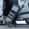 A person is pulling a rolling tool chest out of a van. Voir les images du produit
