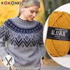 A woman wearing a knitted sweater, with a ball of yarn next to her. Produktbild-Vorschau