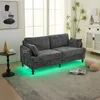 A modern living room with a grey sofa featuring LED lighting and a side table. Produktbild-Vorschau