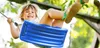 A young girl is happily swinging on a blue swing outdoors. Anteprima dell’immagine prodotto