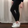 A person is using a shoehorn to put on a white sneaker. Produktbild-Vorschau