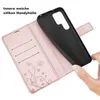 A hand is holding a black phone case, which is being inserted into a rose gold wallet case with card slots and a floral design. Produktbild-Vorschau