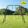 A swing set with two green swings is set up on a grassy lawn with trees in the background. Produktbild-Vorschau