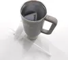 A gray Stanley tumbler with a tan handle is shown on a white surface, with a straw and cleaning brush next to it. Produktbild-Vorschau