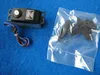 A black servo motor with a wire and a plastic bag of accessories are laid out on a blue surface. Produktbild-Vorschau
