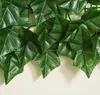 A close-up view of artificial dark green ivy leaves attached to a green grid. Produktbild-Vorschau