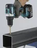 A hand wearing a glove is using a cordless drill to make a hole in a metal pipe. Produktbild-Vorschau