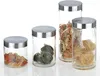 Four glass storage jars with metal lids filled with different types of pasta, arranged on a white background. Náhled obrázku produktu