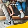 A family sitting on a couch with their feet visible, some wearing socks. Náhled obrázku produktu