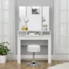 A white vanity table with a tri-fold mirror and a white stool in front of it, with a plant on the left and curtains in the background. Podgląd zdjęcia produktu