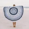 Rundes Strandtuch mit blau-weißem Mandala-Muster, von einer Person an einem Sandstrand gehalten Anteprima dell’immagine prodotto