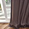 A close-up view of a brown velvet curtain with a damask pattern and a decorative border, partially covering a window and resting on a wooden floor. Produktbild-Vorschau