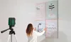 A woman is using a laser level to hang pictures on a wall. Produktbild-Vorschau