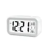 A white digital alarm clock with a black display showing the time, date, and temperature. Voir les images du produit