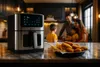 A family is gathered in a kitchen, with an air fryer and a plate of food in the foreground. Náhľad obrázku produktu