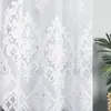 A close-up view of a white lace curtain with a damask pattern. Náhled obrázku produktu