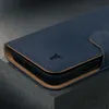 A close-up shot of a dark blue leather iPhone case with a tan interior and a small black logo. Produktbild-Vorschau