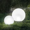 Two illuminated spherical garden lights are placed on a grassy lawn with tall reeds in the background. Produktbild-Vorschau