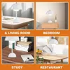 Collage of four images showing a white mushroom-shaped LED table lamp in different settings: a living room, a bedroom, a study, and a restaurant. Produktbild-Vorschau