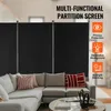 A black, multi-functional partition screen is set up behind a sectional sofa in a living room. The screen has three panels and is supported by metal poles. Decorative pillows in red and white stripes and a red geometric pattern are on the sofa. A coffee ta Voir les images du produit
