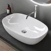 A white ceramic vessel sink with a chrome faucet on a dark countertop. Produktbild-Vorschau