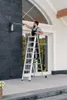A man is standing on a ladder cleaning a light fixture on a dark stone wall next to a large window. Produktbild-Vorschau