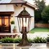 A vintage-style outdoor lamp is placed on a patio in front of a house. Produktbild-Vorschau