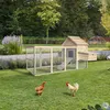 A wooden chicken coop with an attached run is set up on a green lawn in a garden setting. Two chickens are visible in the foreground. Anteprima dell’immagine prodotto