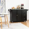 A black kitchen cart with a stainless steel top is shown in a room with a table and a rug. Náhľad obrázku produktu