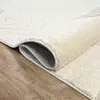 A close-up view of a rolled-up rug on a wooden floor. Produktbild-Vorschau