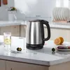 A stainless steel electric kettle is displayed on a kitchen counter with a glass of water and some fruit. Produktbild-Vorschau