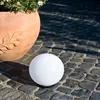 A white sphere light sits on a cobblestone path next to a terracotta pot with flowers. Produktbild-Vorschau