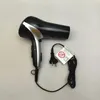 A black and silver hair dryer with its cord and a warning tag. Produktbild-Vorschau