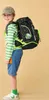 A young boy wearing a backpack and casual clothes, standing against a plain background. Náhled obrázku produktu