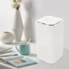 A white air purifier sits on a table next to a mug and some books, with vases in the background. Podgląd zdjęcia produktu
