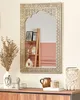 A decorative mirror with a gold metal frame is displayed on a wooden dresser, surrounded by various decorative items. Náhľad obrázku produktu