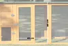 A close-up view of a wooden chicken coop with wire mesh doors and measurement indicators. Produktbild-Vorschau