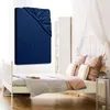 A dark blue fitted sheet is displayed prominently in the foreground, with a bed and bedroom furniture in the background. Produktbild-Vorschau