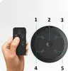A hand holding a remote control next to a black circular fan. Podgląd zdjęcia produktu