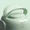 Close-up of the top of a sage green rice cooker, focusing on the handle and lid. Produktbild-Vorschau